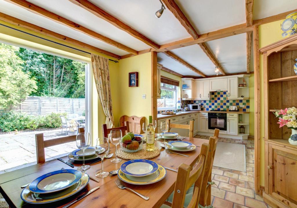 a kitchen and dining room with a wooden table and chairs at Woodbine Cottage in Saint Hilary