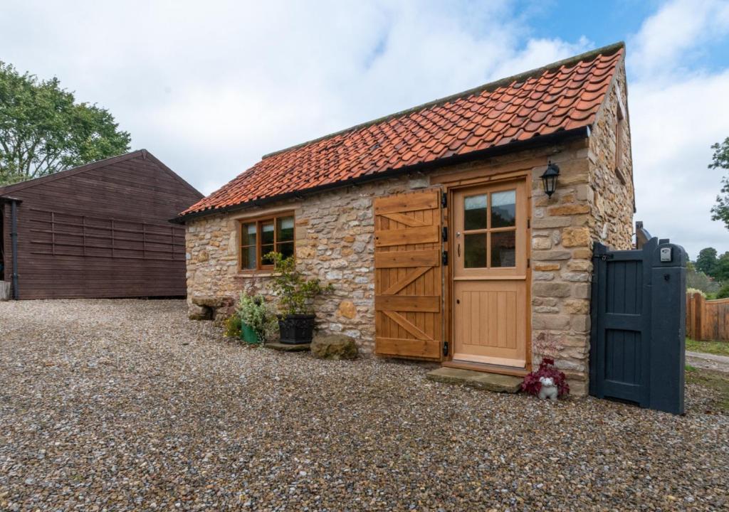 ein Cottage aus Stein mit einer Holztür und einer Garage in der Unterkunft The Hayloft in Nawton