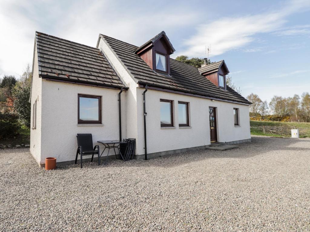 a white house with a table and a chair at Balnabodach in Inverness