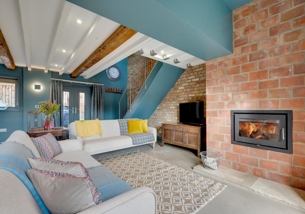 a living room with a brick wall and a fireplace at The Granary at The Foldyard in Holme upon Spalding Moor