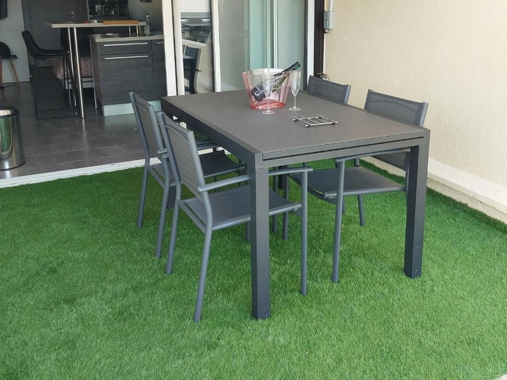 een eettafel met stoelen op groen gras bij Studio Heliopolis Naturiste in Cap d'Agde