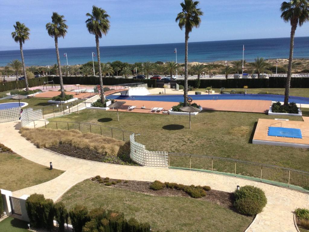 um parque com piscina e palmeiras e o oceano em Beachfront penthouse with sunroof em Arenales del Sol
