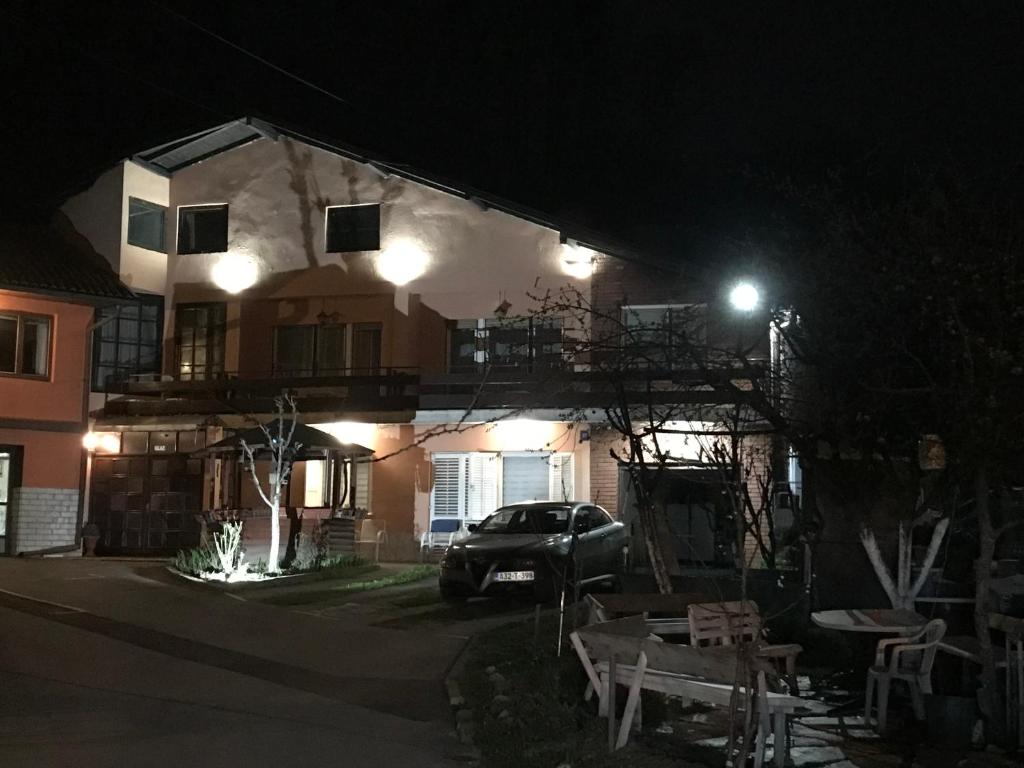 圖茲拉的住宿－Prenociste Chardak，夜间停在房子前面的汽车