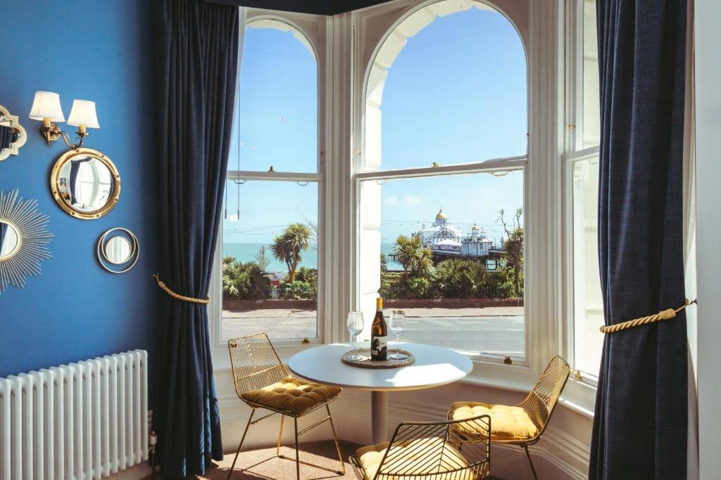 a table and chairs in a room with a large window at Pier Reflections - seafront apartment in Eastbourne