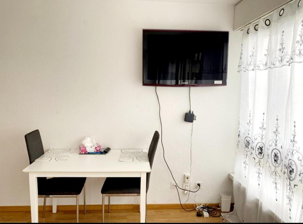 een witte tafel met twee stoelen en een televisie aan de muur bij Kleine Wohnung im Zentrum Bern nähe Marzili in Bern