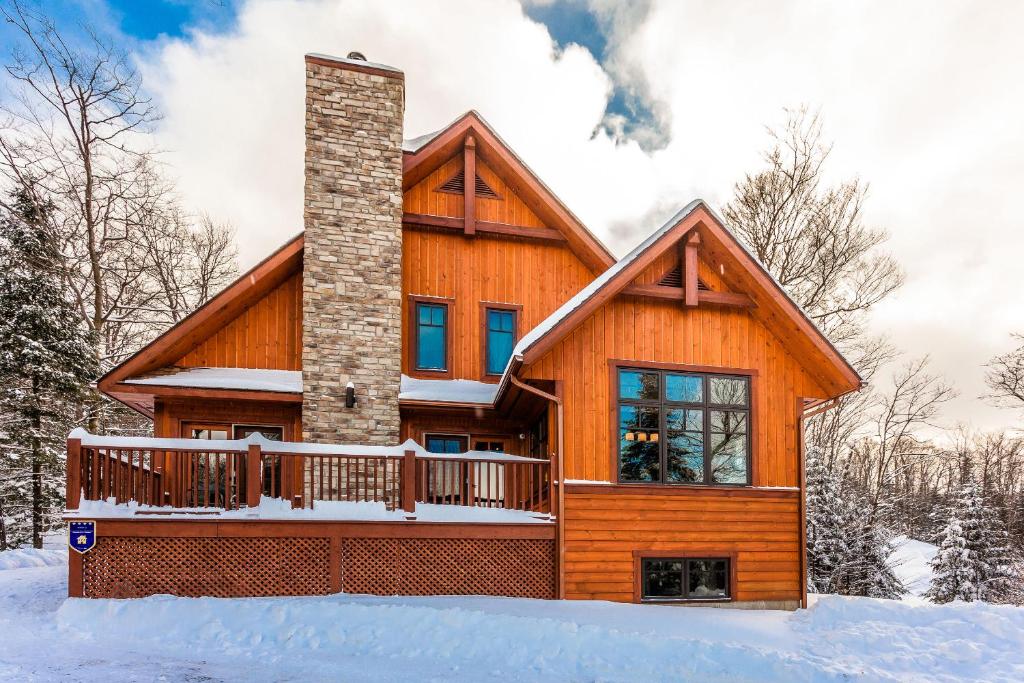 a log home with a deck in the snow at Chalet Le Mont-Blanc in Saint-Faustin