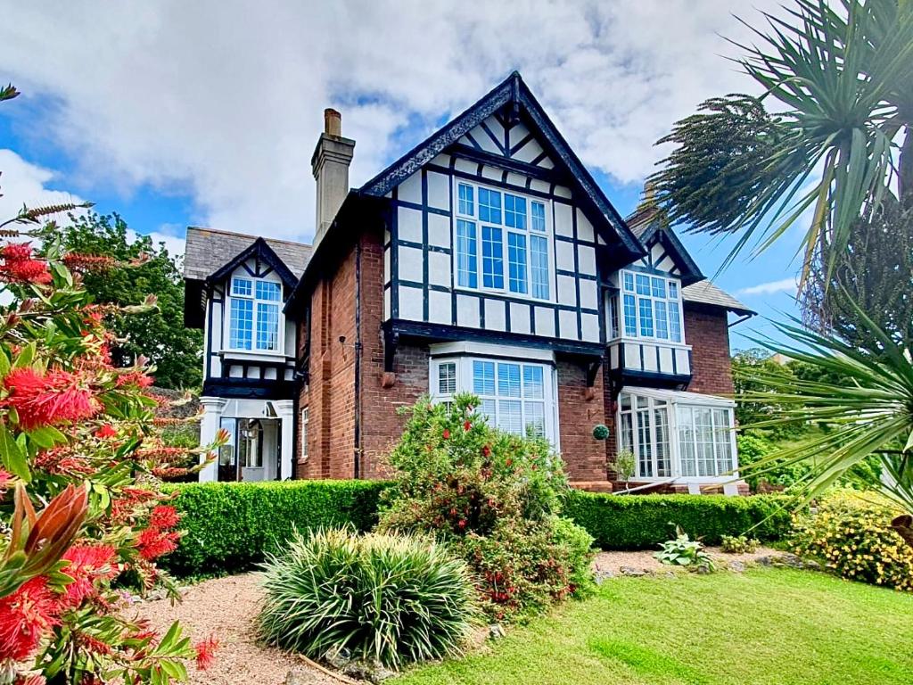 Una gran casa de ladrillo con ventanas azules y arbustos en The Torcroft Apartments at Bedford House, en Torquay