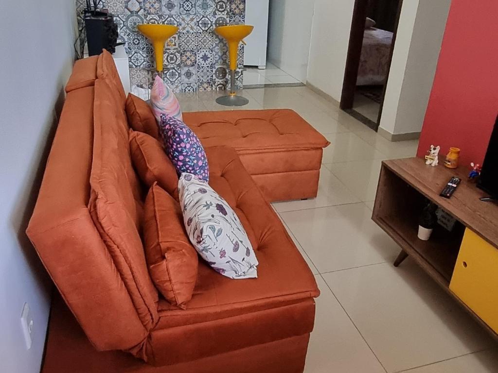 an orange couch with pillows on it in a living room at Apartamento Vila Aconchego Vermelho in Salvador