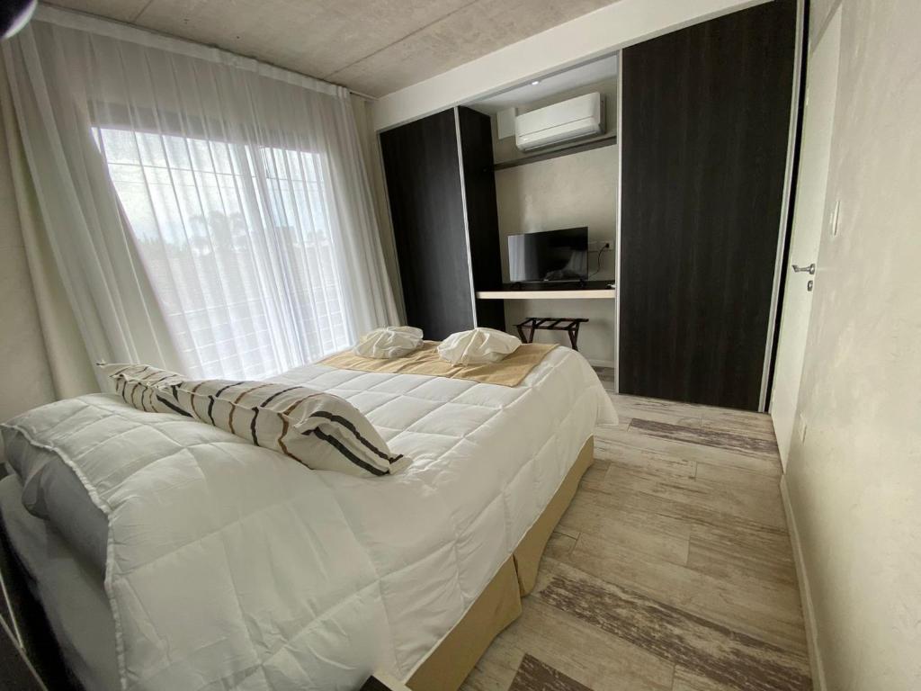 1 dormitorio con 1 cama blanca grande y ventana en Glo apart hotel en Cañuelas