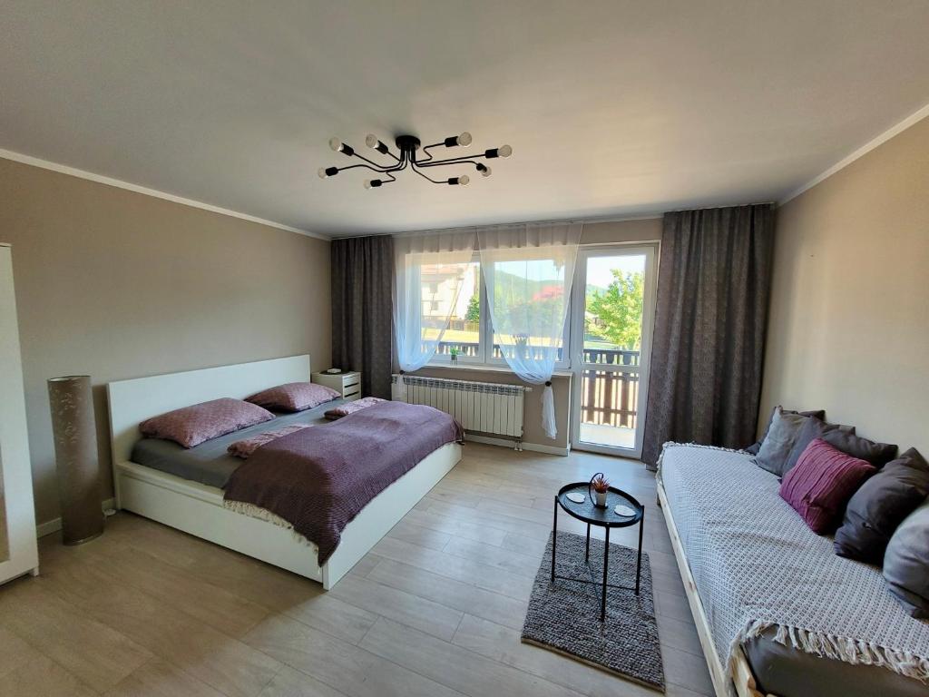 a bedroom with a bed and a couch at Studio 2-pokojowe z balkonem z widokiem na góry in Międzybrodzie Żywieckie