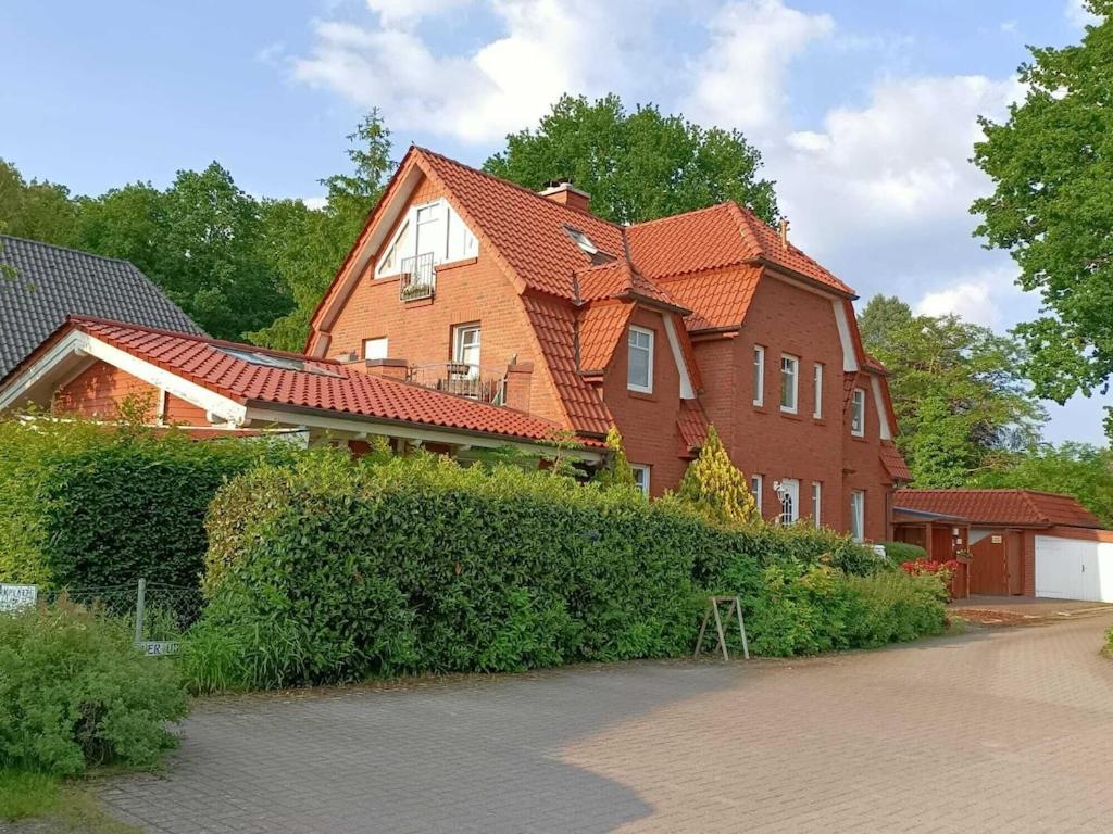 une grande maison en briques avec un toit orange dans l'établissement Moderne Ferienwohnung mit Kamin u Garten im EG 100qm Nähe Weser und Golfplatz, à Achim