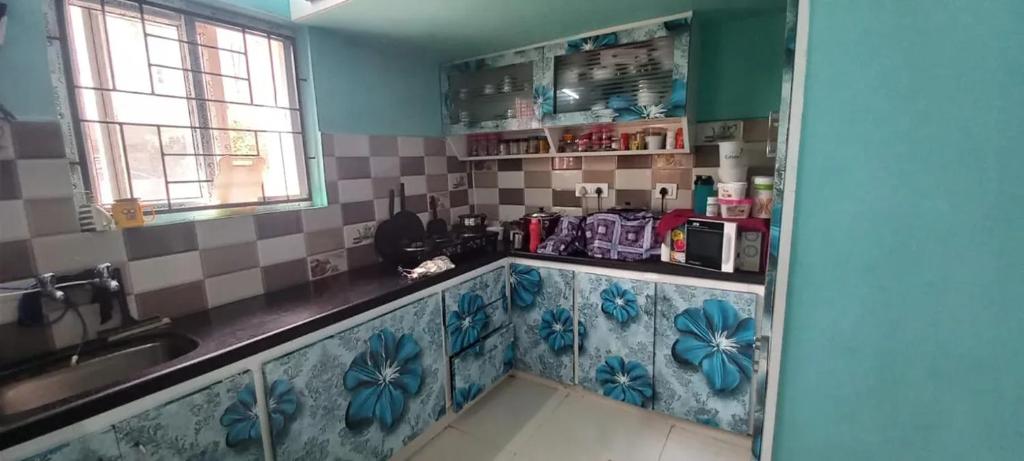 een keuken met een wastafel en blauwe en witte tegels bij Assan Place in Bhubaneshwar