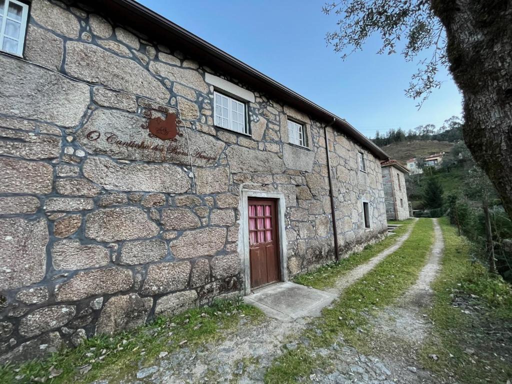 ein altes Steingebäude mit einer roten Tür auf einer Straße in der Unterkunft Casa do Portelinha in Vieira do Minho