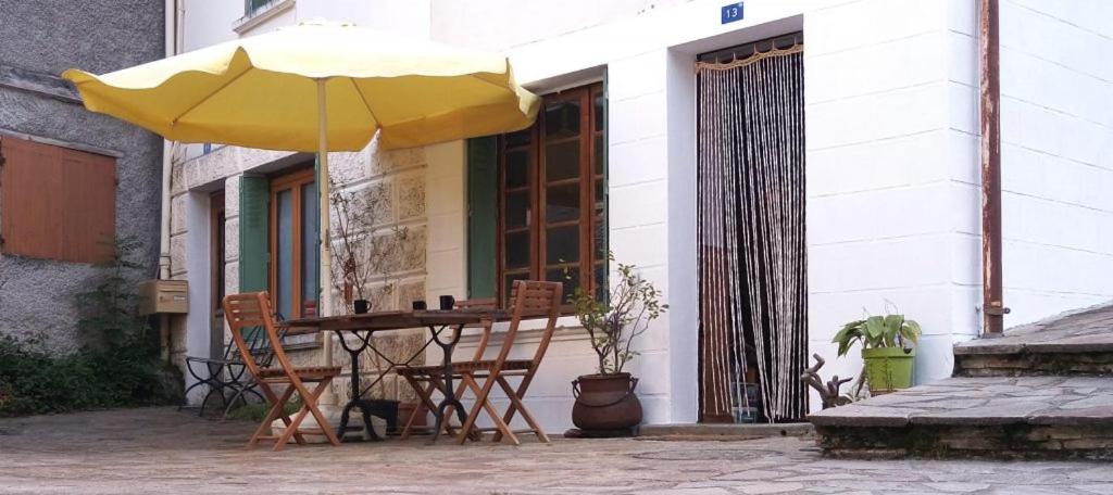 einen Tisch und Stühle mit gelbem Regenschirm auf einer Terrasse in der Unterkunft Le Gîte du Rocher - Auzat in Auzat