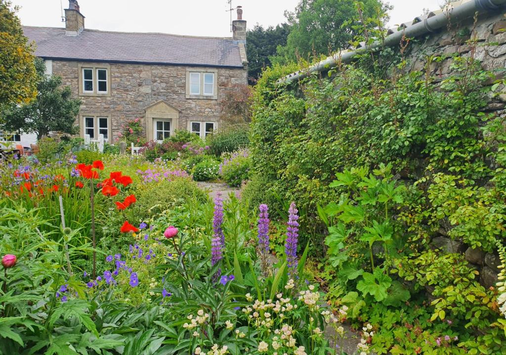 a garden with flowers in front of a stone house at South View Cottage in Horton in Ribblesdale