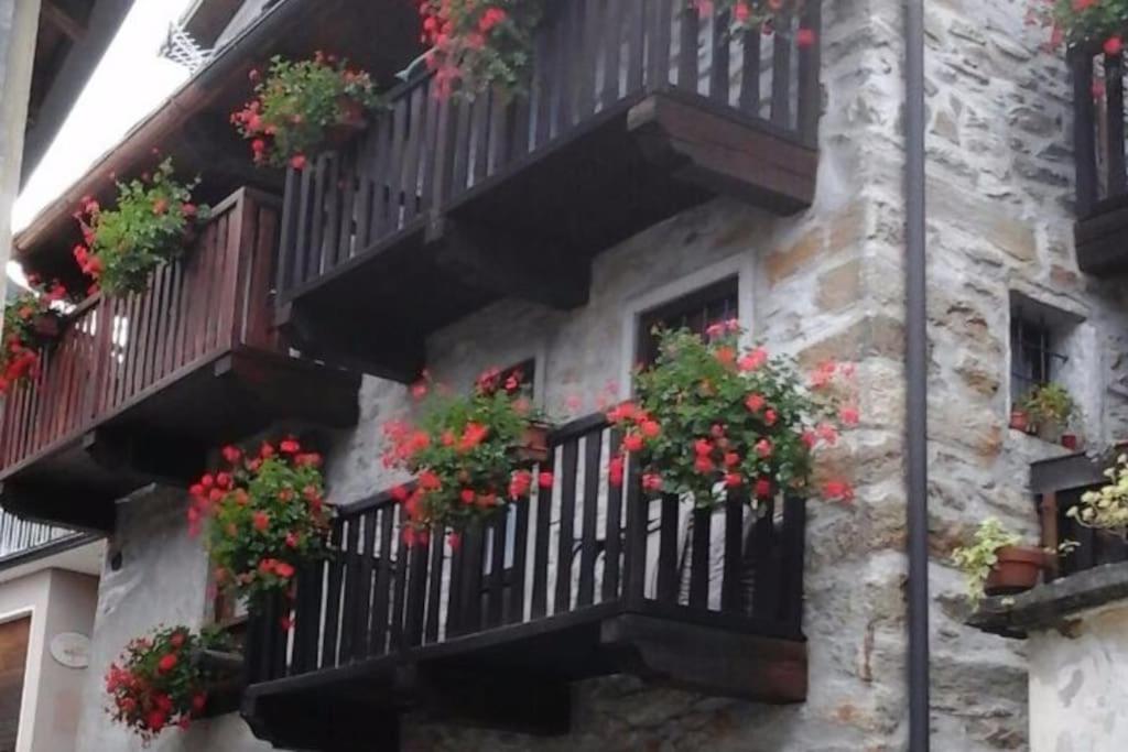 un edificio de piedra con macetas en los balcones en La Cà Rustica - casa vacanze, en Bognanco