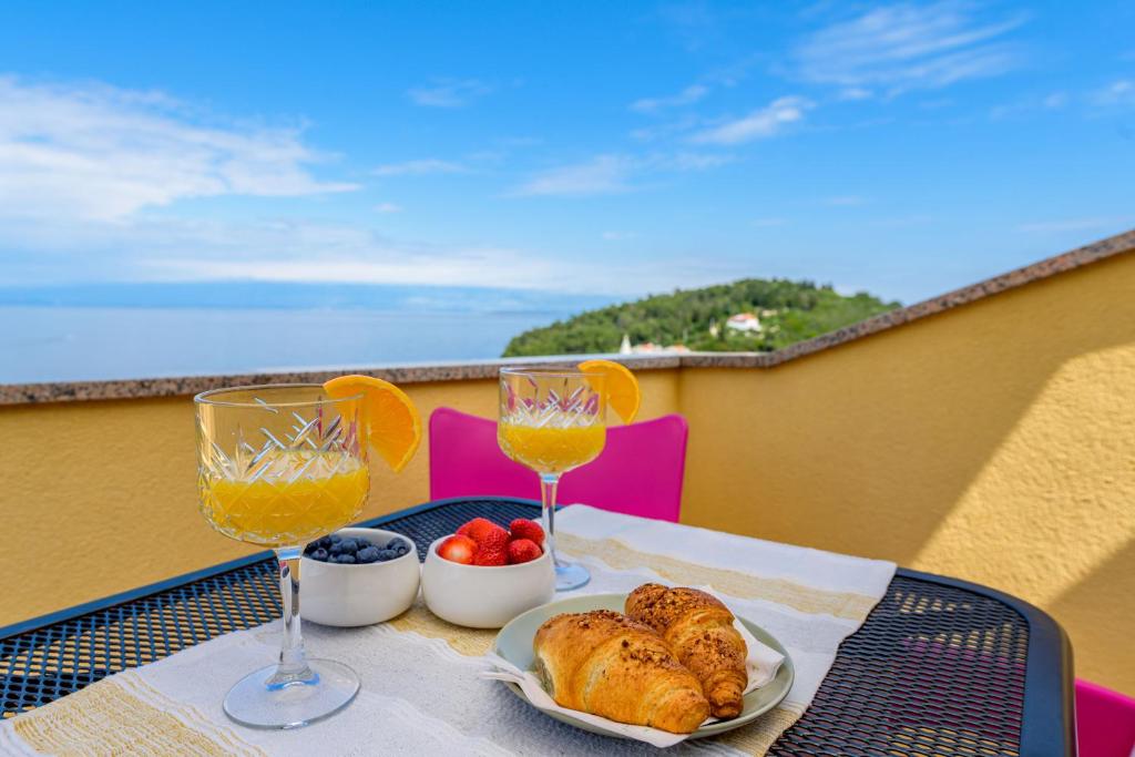 een tafel met een bord eten en twee glazen wijn bij House Rosa in Mali Lošinj