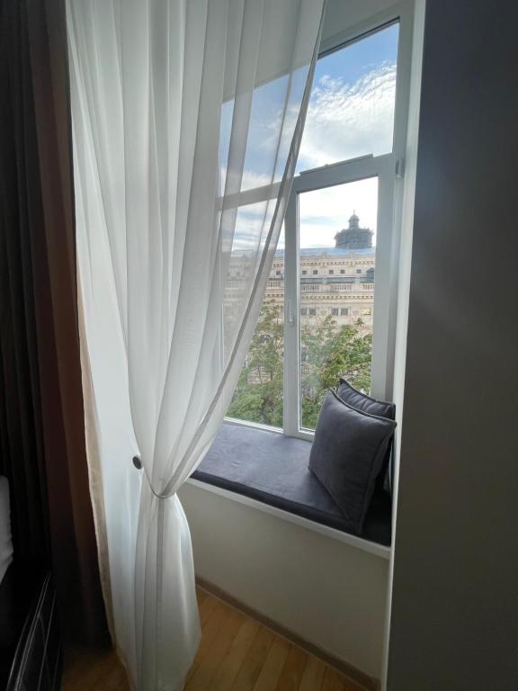 een stoel bij het raam met een gordijn en een kussen bij Apartment with the view of the Opera House in Lviv
