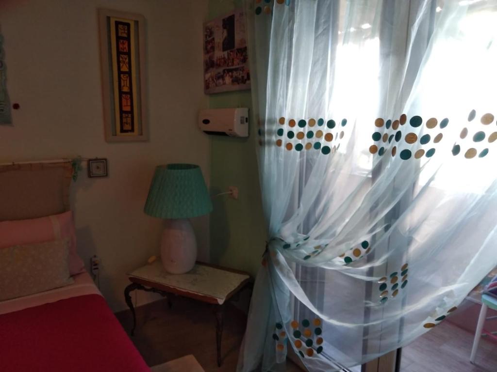 sala de estar con sofá y ventana en Stanza privata casa artistica Mariola, en San Sperate