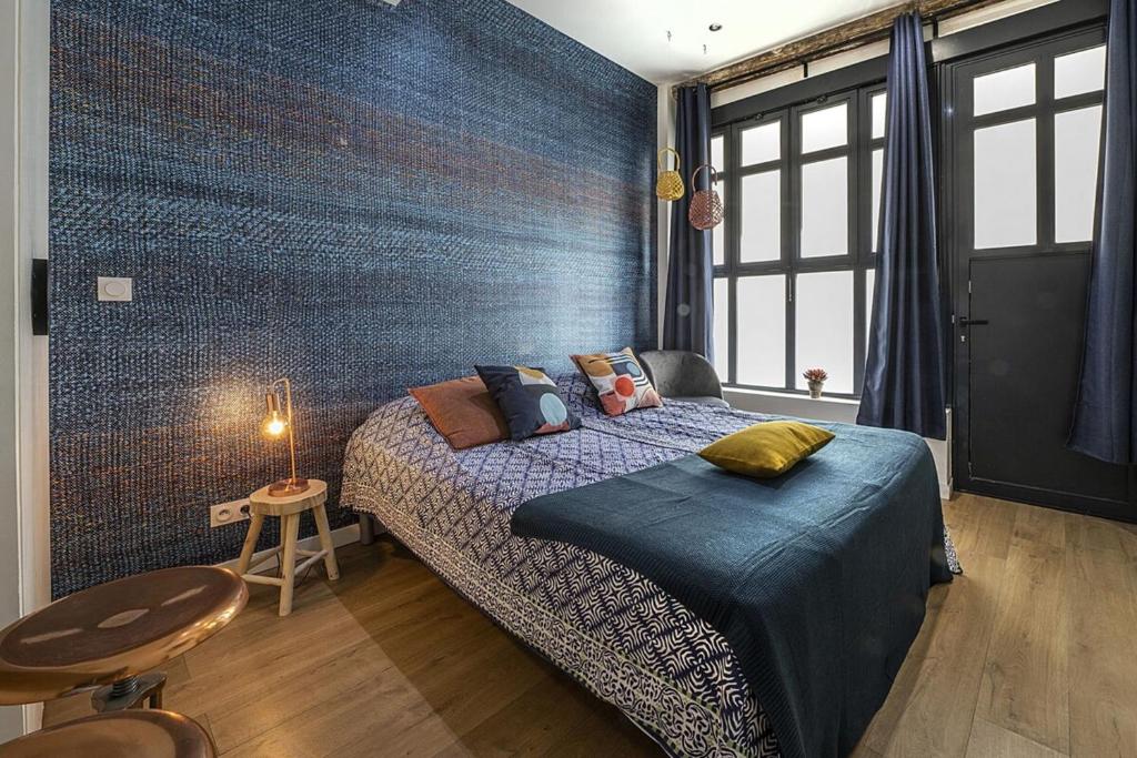 a bedroom with a bed and a blue wall at Le petit Claude Bernard - studio cosy Bellecour in Lyon