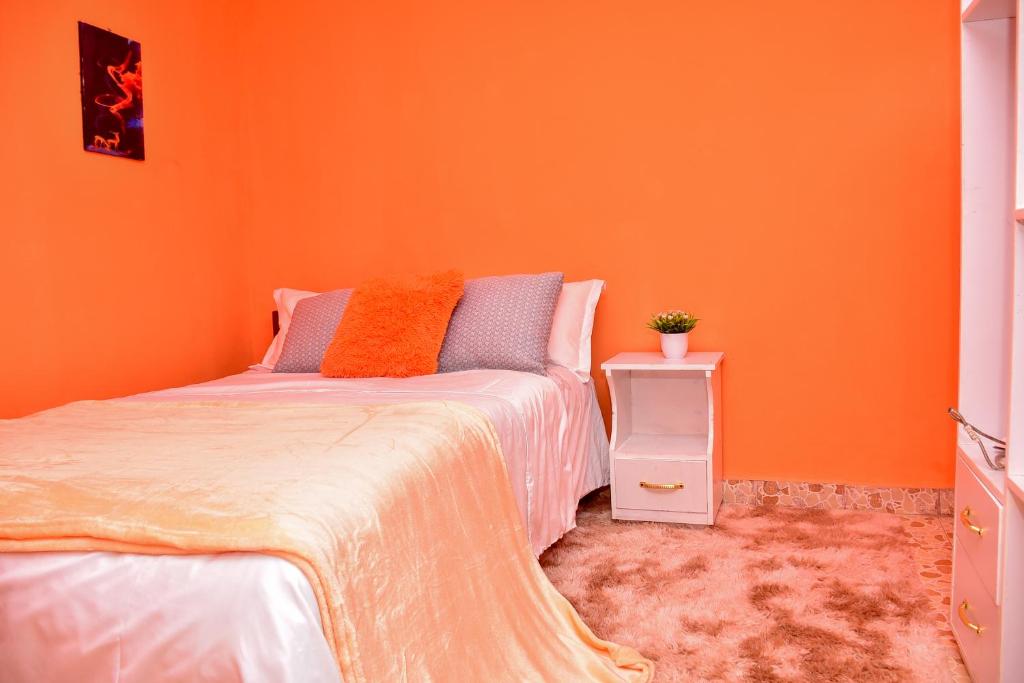 a bedroom with an orange wall and a bed at CasaAloha Homes- Cozy 1Bdr - Along Eldoret-Kisumu Highway - Near the Edge Bar and Restaurant in Eldoret