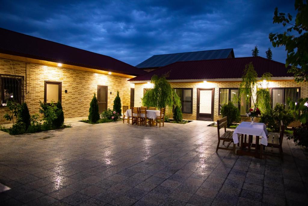 a patio with tables and chairs in front of a building at Gostevoy Dom Гостевой Дом in Sheki