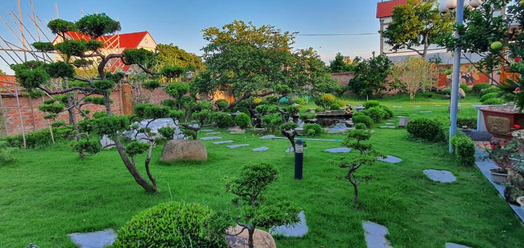 a garden with trees and rocks in the grass at Mộc House (Green House) 