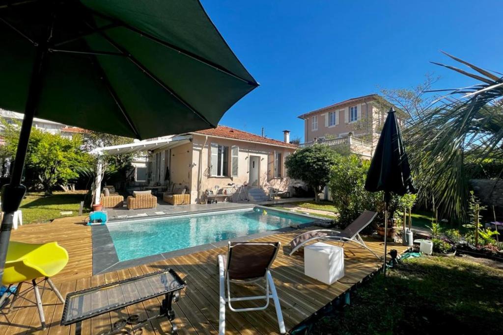 uma piscina com cadeiras e um guarda-sol e uma casa em Holiday house in the city-center of Antibes with a private pool em Antibes