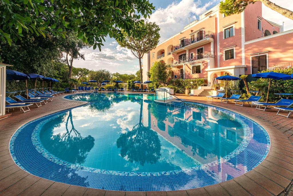 Hotel San Valentino Terme في ايسكيا: مسبح كبير والكراسي الزرقاء والمظلات