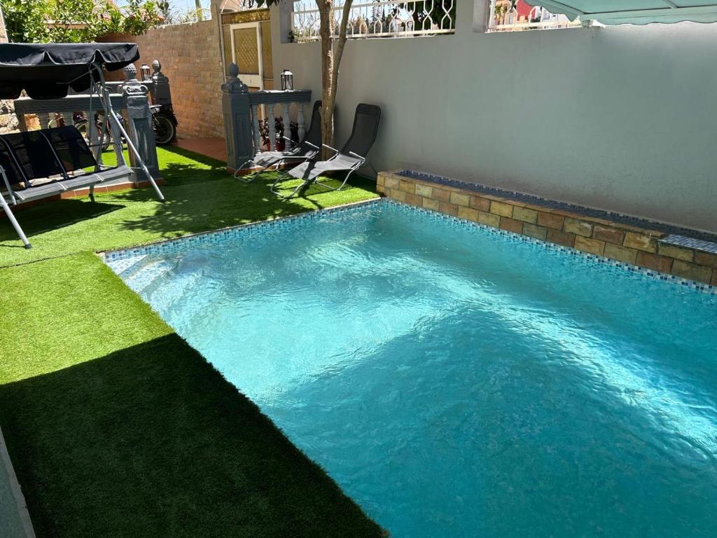 a swimming pool with blue water in a yard at Dar el kebira in Meknès