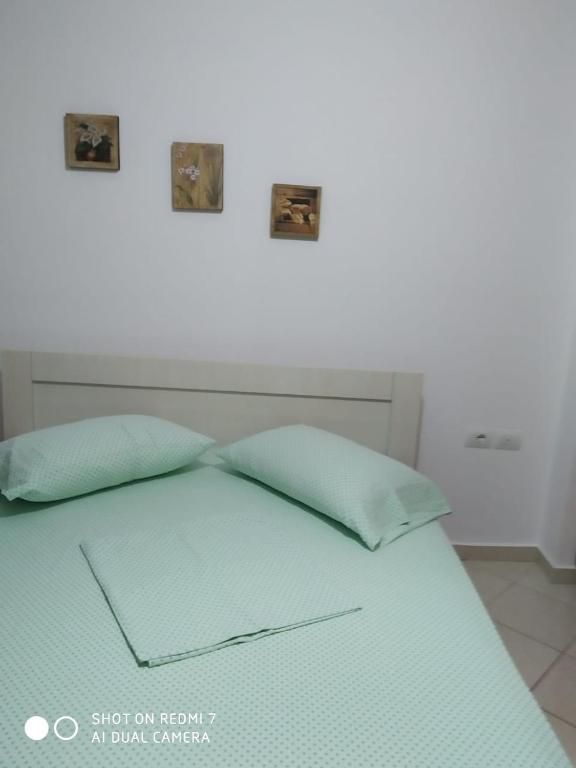 Una cama con dos fotos encima. en Primavera Apartments, en Sarandë