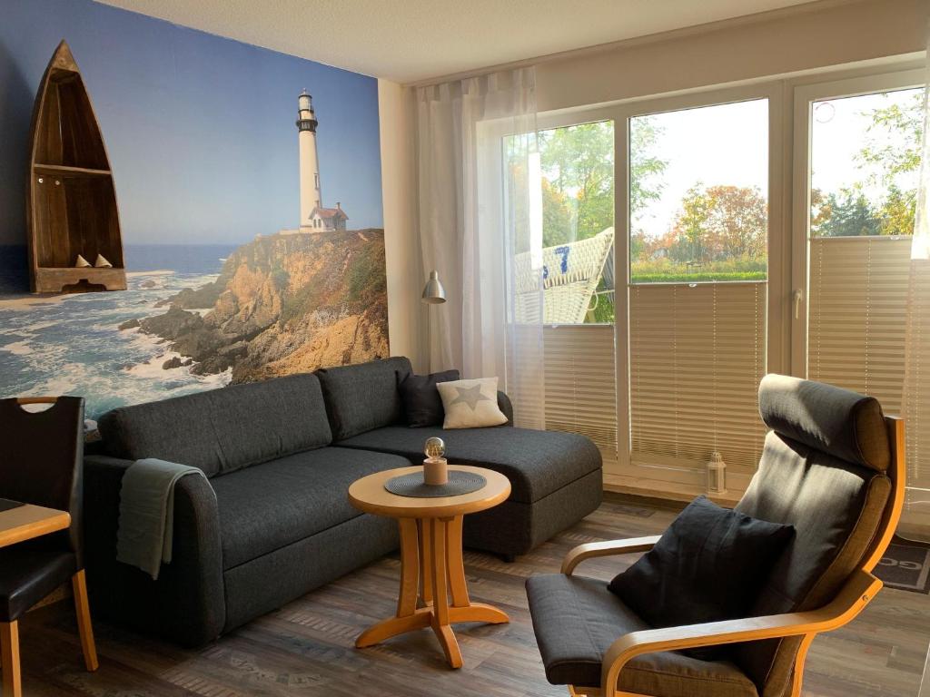 ein Wohnzimmer mit einem Sofa und einem Wandbild des Leuchtturms in der Unterkunft Yachthafenresidenz - Wohnung 9103 / 879 in Kühlungsborn