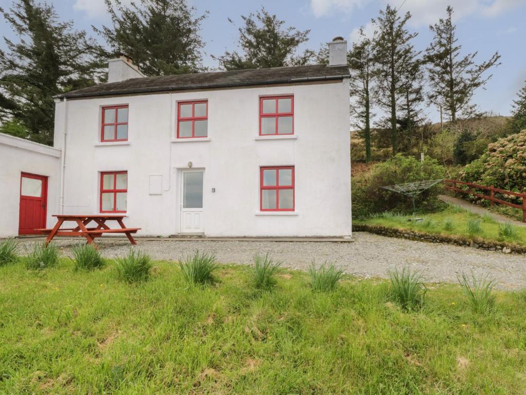 a white house with red windows and a picnic table at Sea View House in Renvyle