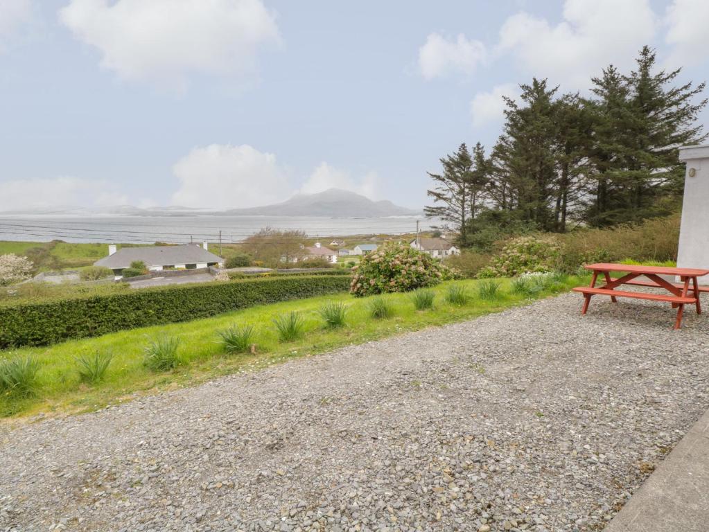 a red bench sitting on the side of a gravel road at Sea View House in Renvyle