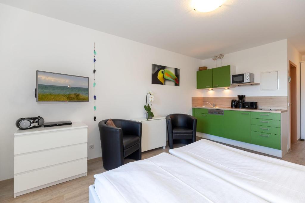 ein Schlafzimmer mit einem Bett und eine Küche mit grünen Schränken in der Unterkunft Yachthafenresidenz - Wohnung 8105 / 9733 in Kühlungsborn