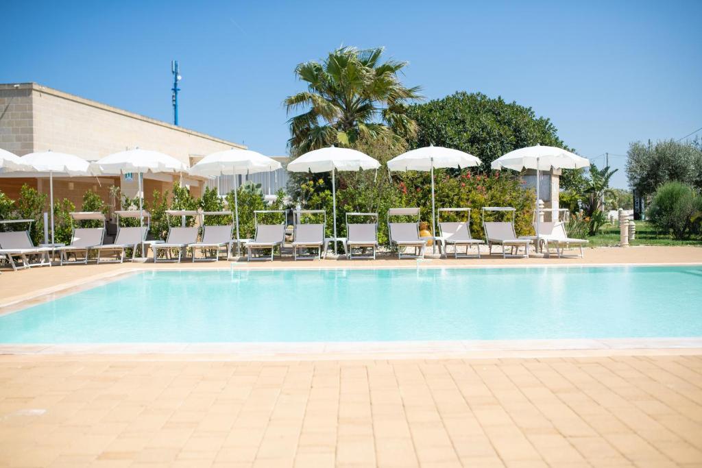 a large swimming pool with chairs and umbrellas at Hotel Reverse in Torre Santa Sabina