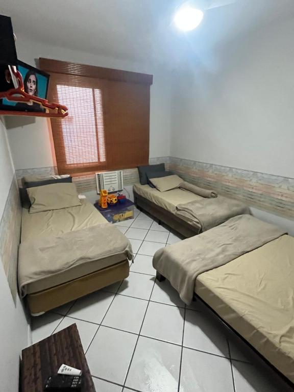 Habitación con 2 camas y mesa. en Nosso apê no Guarujá - Unidade Aquário en Guarujá
