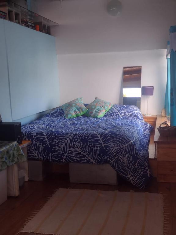 a bed with a blue comforter and pillows in a bedroom at Espacio de arte físico in Buenos Aires