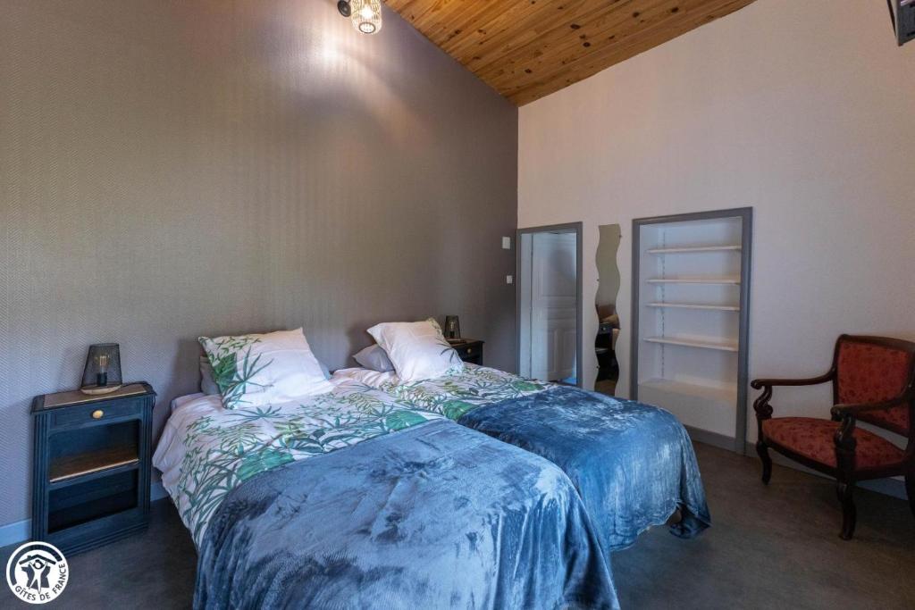 Chambre d'hôte de la petite toscane d'Auvergne في Isserteaux: غرفة نوم بسرير وبطانية زرقاء وكرسي
