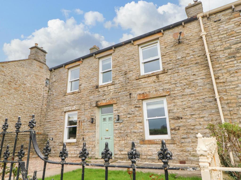 un antiguo edificio de ladrillo con una puerta verde en Hillside House, en Leyburn