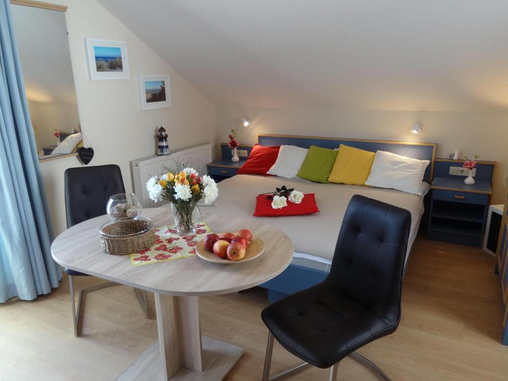 キュールングスボルンにあるYachthafenresidenz-Wohnung-5306-817のベッド1台、テーブル(フルーツ付)が備わる客室です。