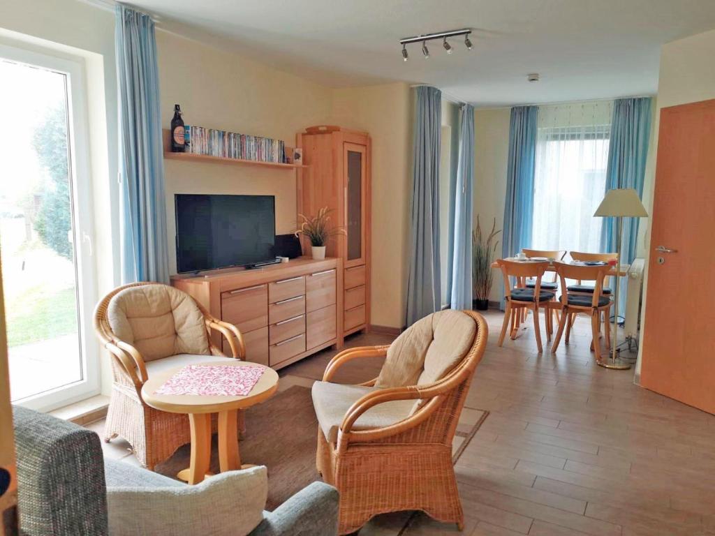a living room with a tv and chairs and a table at Yachthafenresidenz-Wohnung-6106-824 in Kühlungsborn