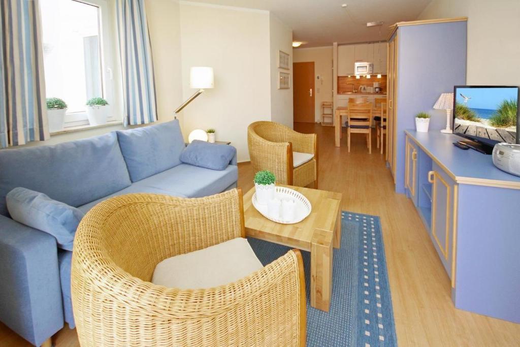 a living room with a blue couch and wicker chairs at Yachthafenresidenz-Wohnung-8308-863 in Kühlungsborn