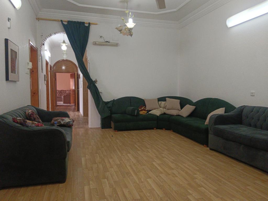 uma sala de estar com um sofá verde e cadeiras em شقة مفرشه مزدلفة em Abha