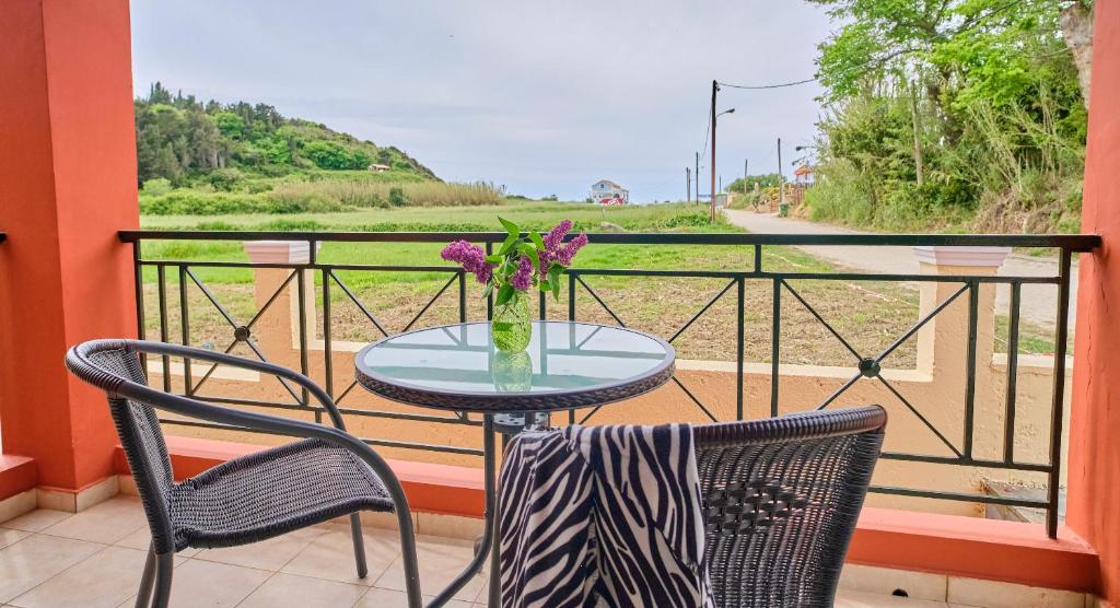 a table with a vase of flowers on a balcony at Logas Beach Studios Peroulades Corfu in Peroulades
