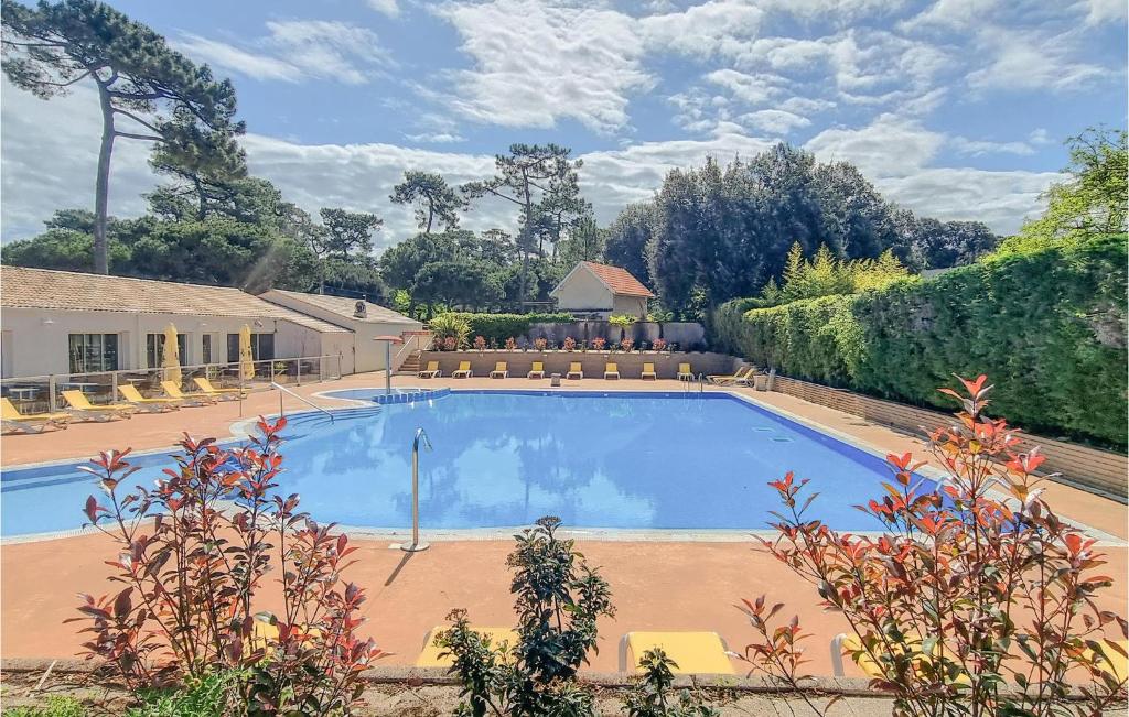 a large blue swimming pool with chairs and trees at Stunning stacaravan In Saint-georges-de-didon With Heated Swimming Pool in Saint-Georges-de-Didonne