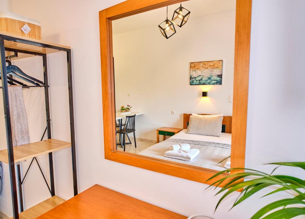 a mirror in a bedroom with a bed and a table at Logas Beach Studios Peroulades Corfu in Peroulades