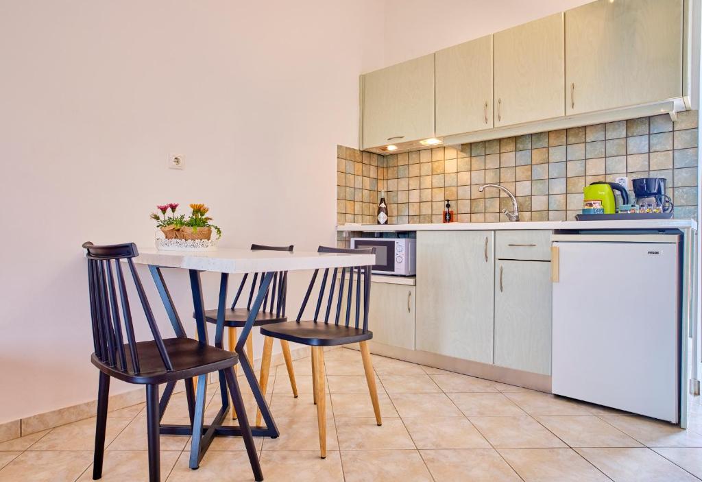 a kitchen with a table and chairs and a refrigerator at Logas Beach Studios Peroulades Corfu in Peroulades