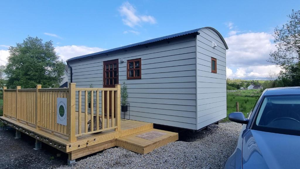 a tiny house with a porch and a car at LittleGreenGlamping in Leitrim