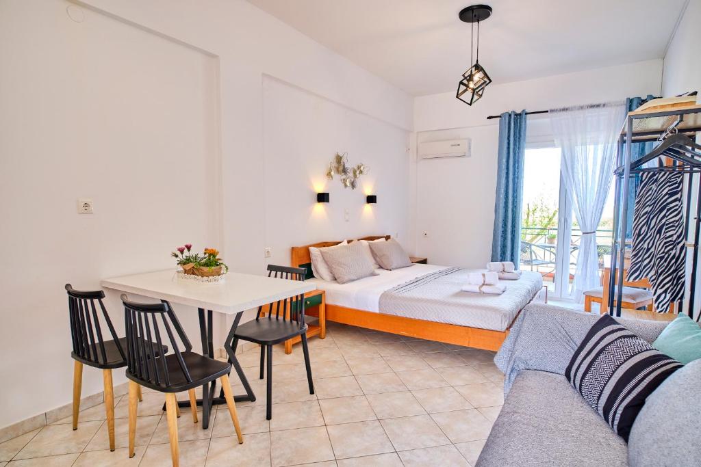 a bedroom with a bed and a table and a couch at Logas Beach Studios Peroulades Corfu in Peroulades